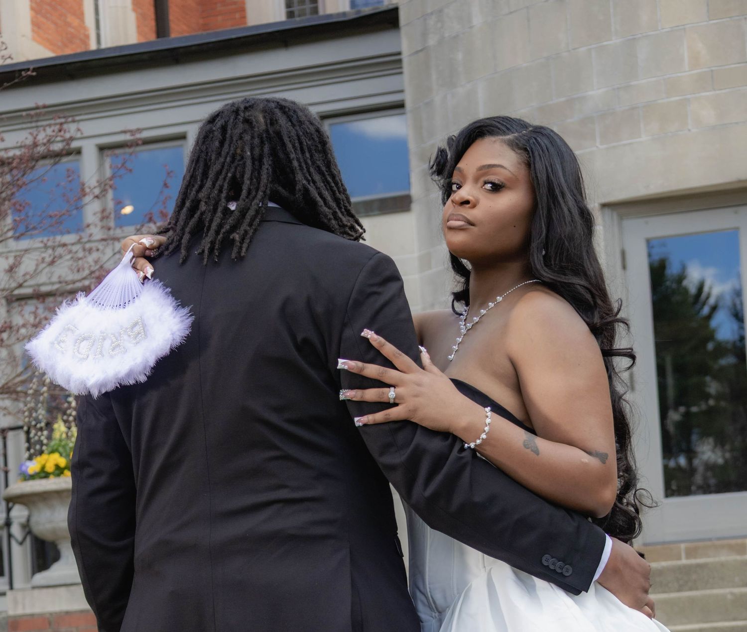 Two people in formal wear share an intimate moment outside a stone building.