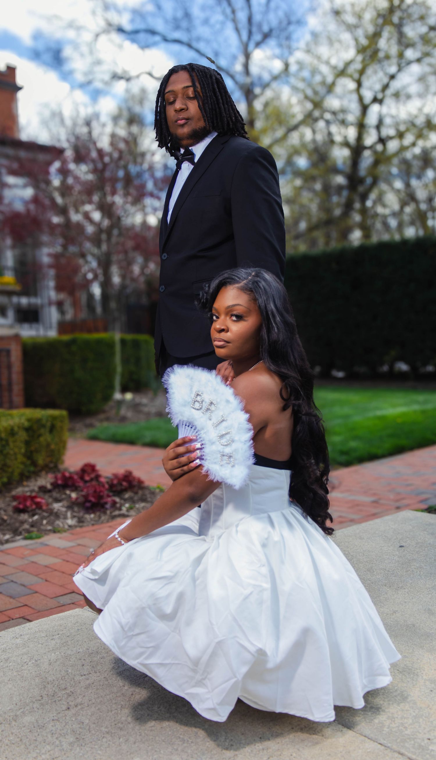 A couple in formal wear poses dramatically on outdoor steps.