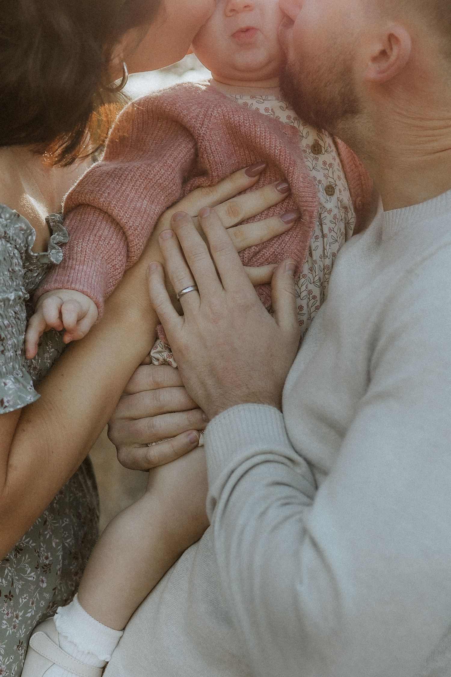 detail photo, mom and dad kissing baby girl, hands