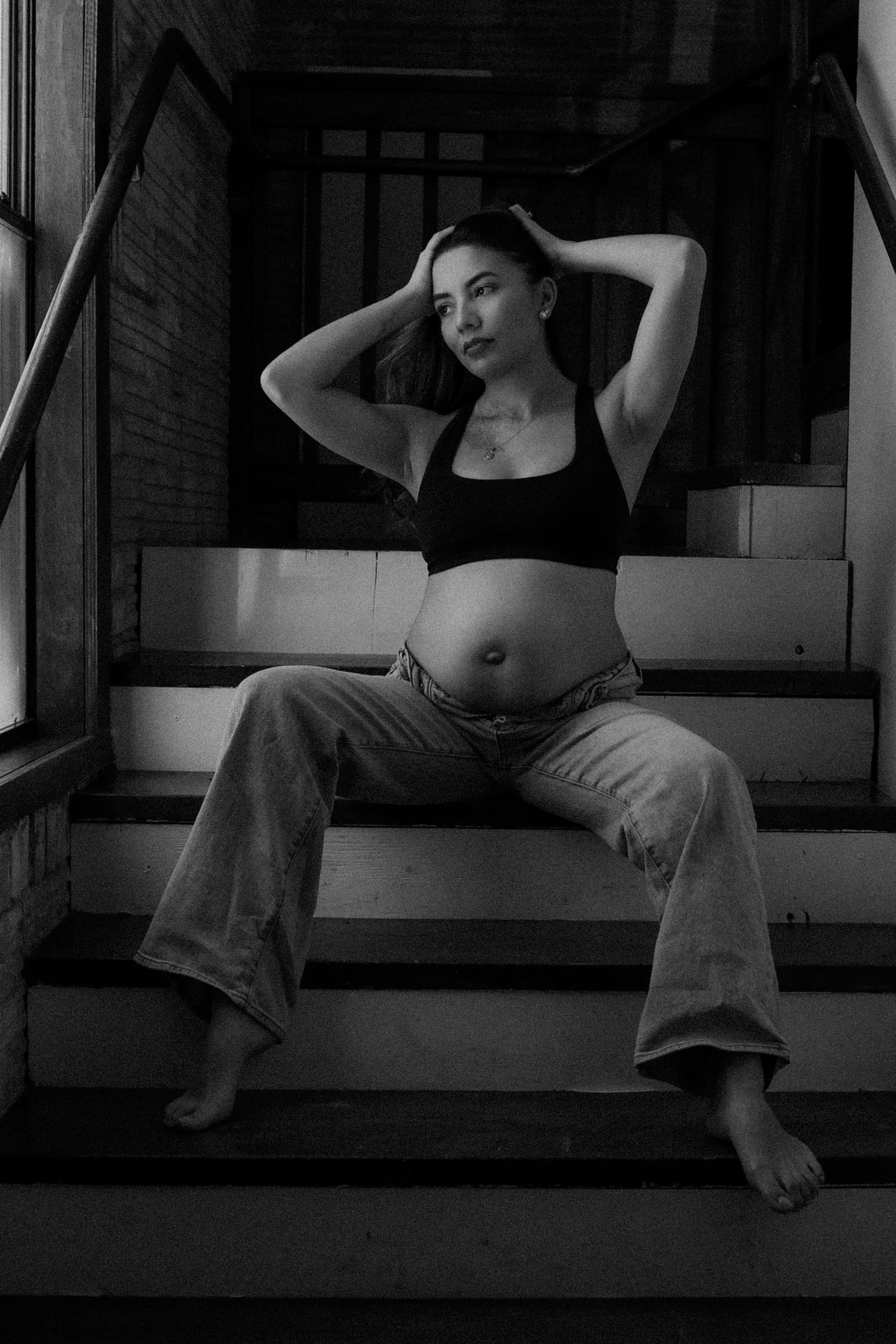 Black and white artistic photo series showing a person in casual attire lounging on wooden stairs in different poses. maternity, mom to be