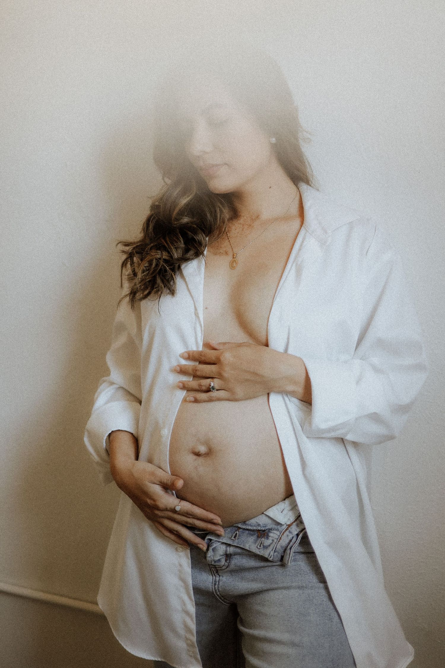 A series of artistic photos showing someone in a white button-down shirt and jeans against a light background. maternity, baby bump