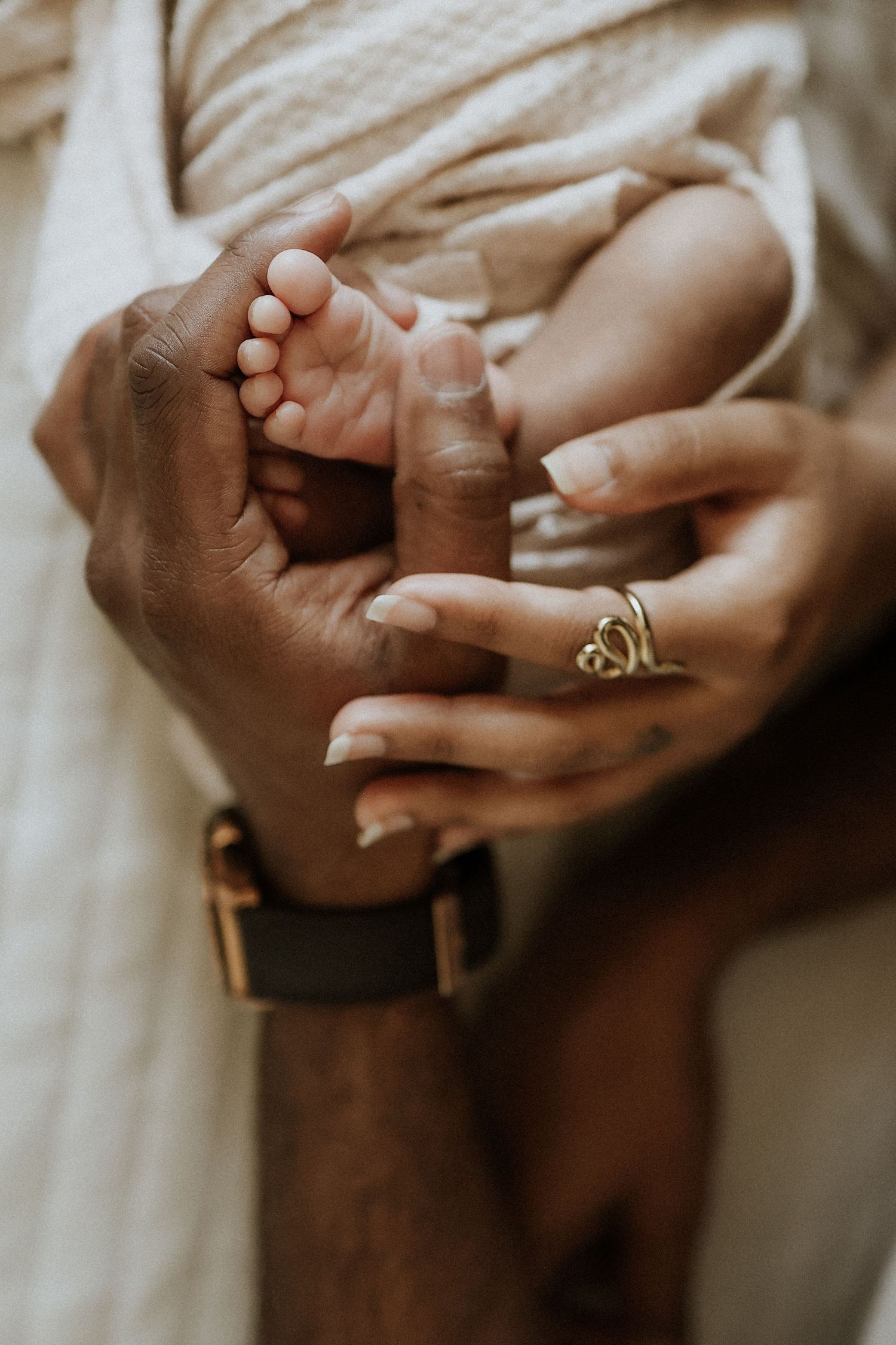 detail hands mom and dad holding baby's foot