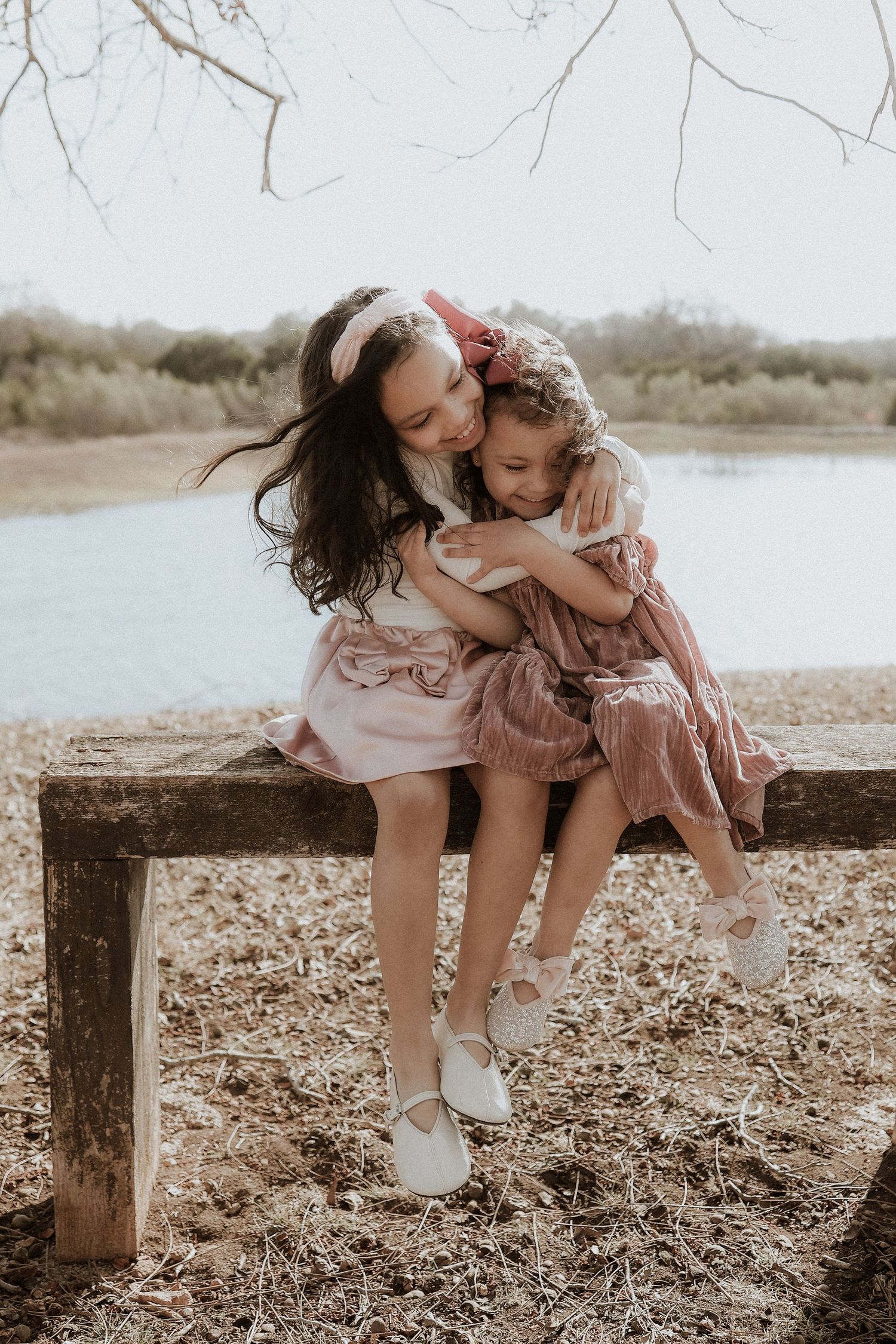 sisters candid photograph at a lake, sitting on a bench, texas hill country