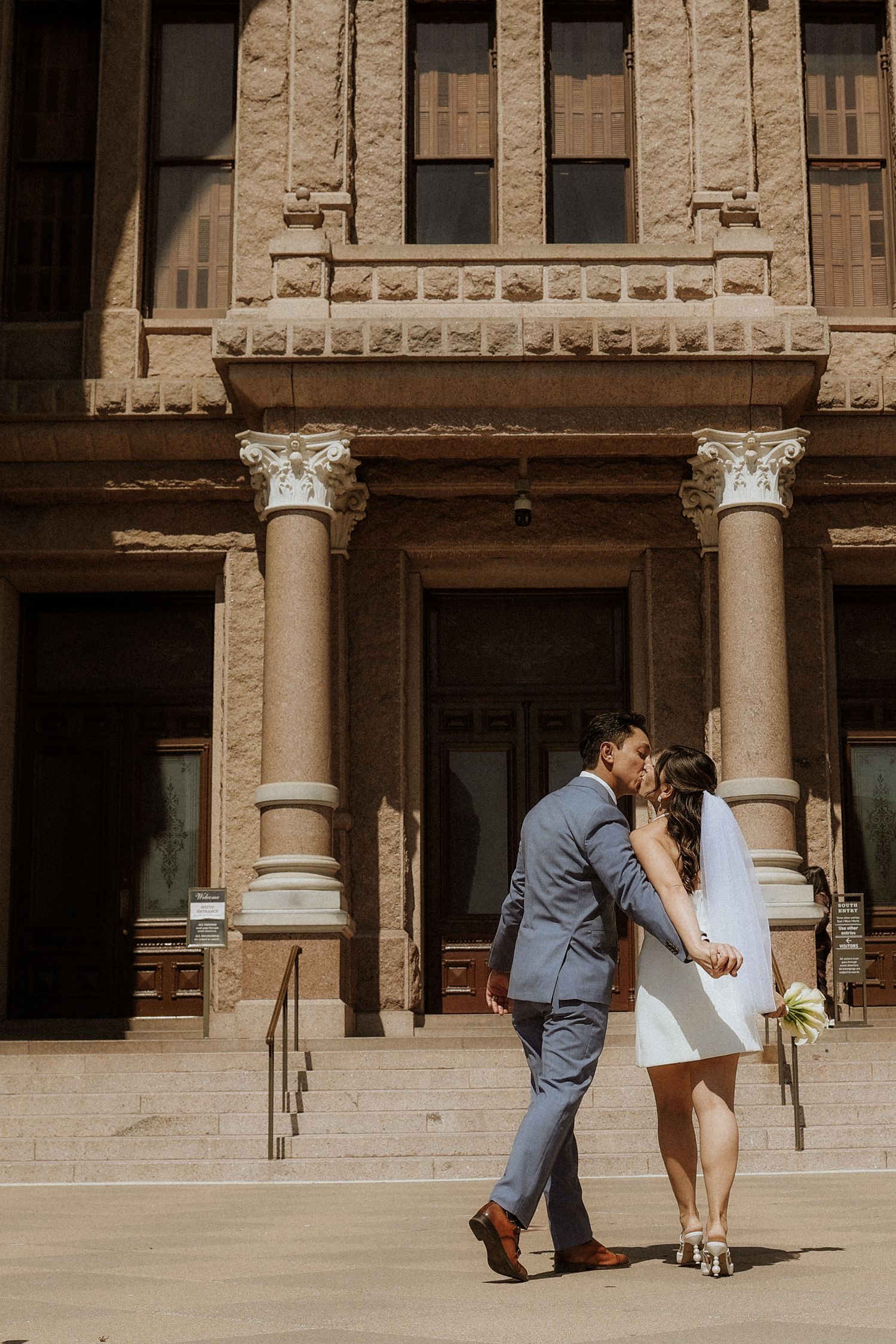 wedding outside texas capitol, bride and groom kissing