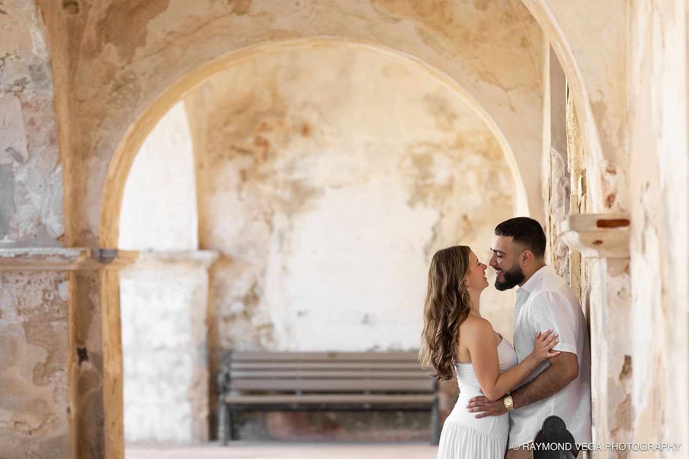 Couple sharing a romantic moment under stone arches of a historic building Castillo de San Cristóbal Puerto Rico