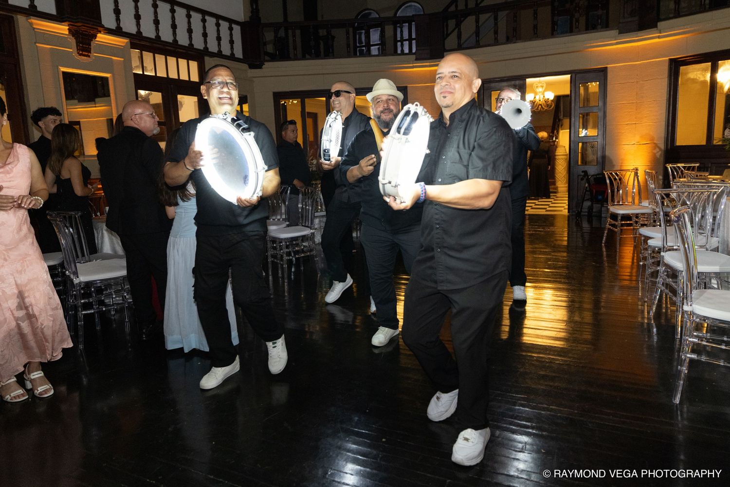 Elegantly dressed guests dance at a formal black and white themed event in a decorated ballroom venue.
