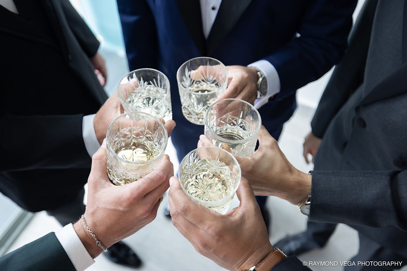 Group of men in suits toasting with crystal glasses of champagne at a formal celebration event.