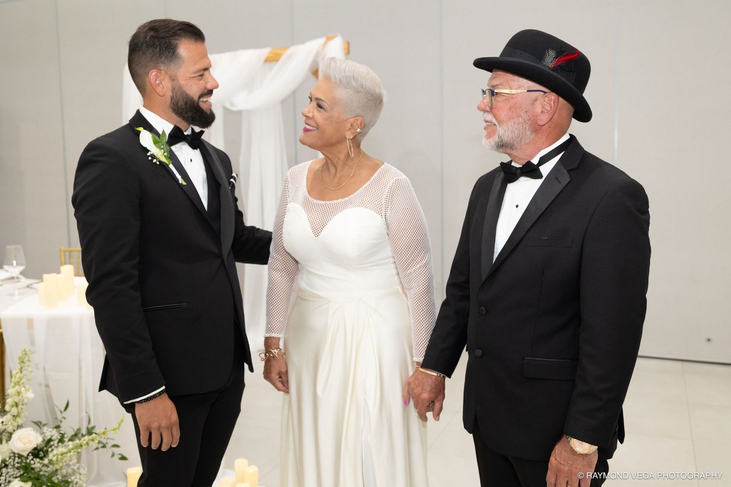 Elderly couple in wedding attire with groom in tuxedo at elegant wedding ceremony venue.