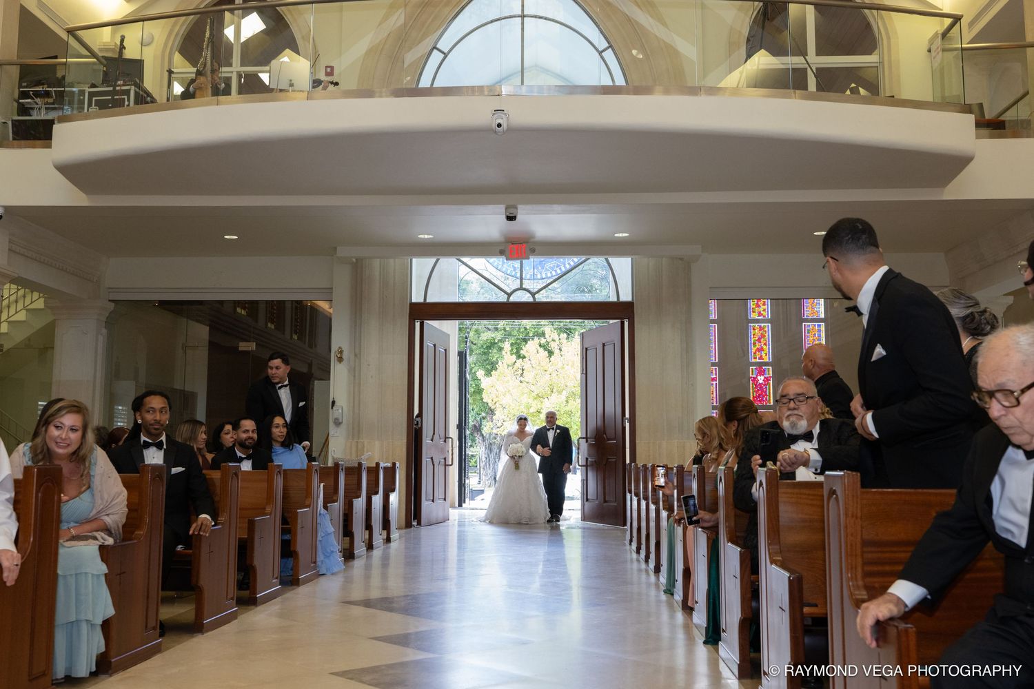 Bride walking down the aisle in an elegant church wedding ceremony with guests seated in wooden pews.