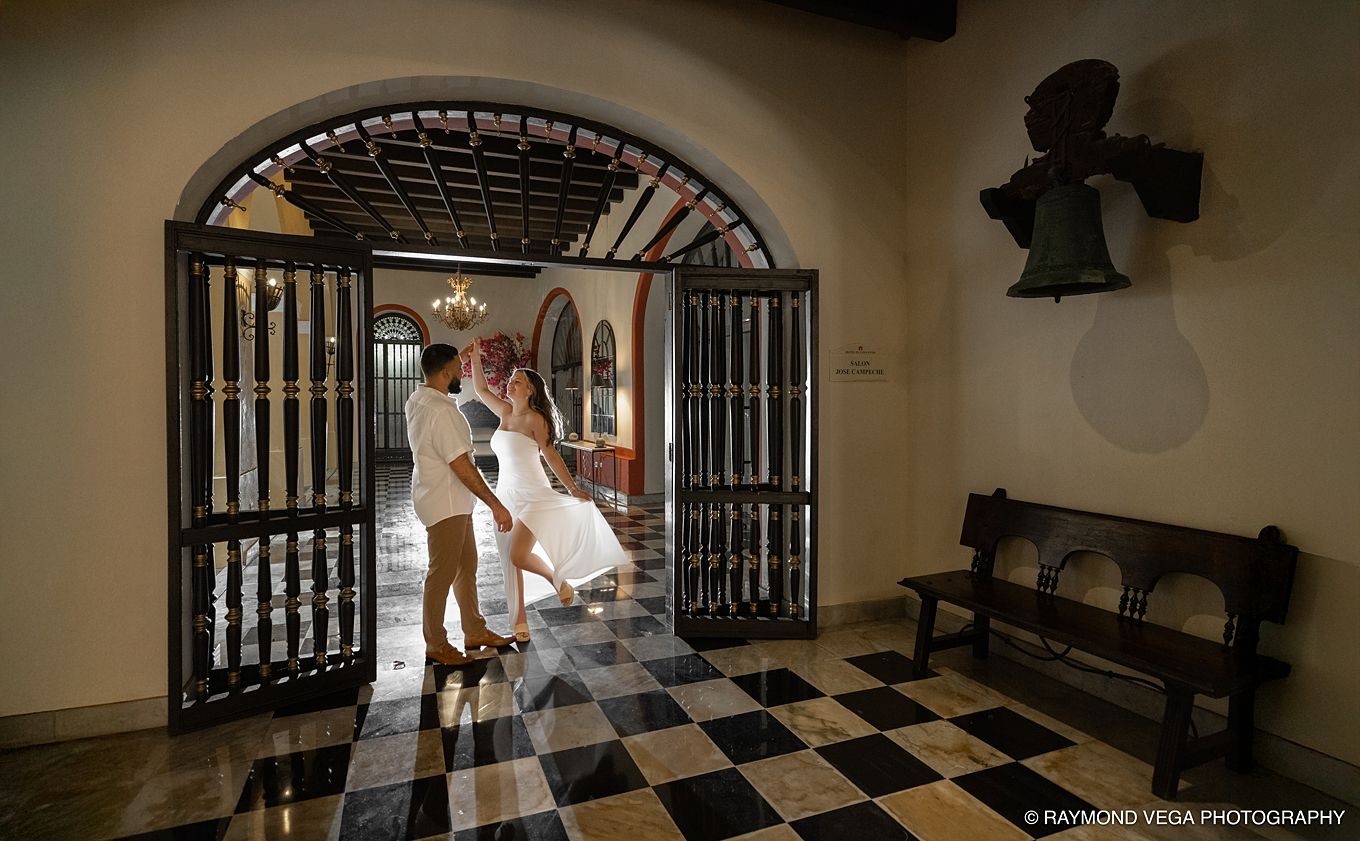 Couple dancing in elegant venue with checkered floors, ornate wooden doors, and chandelier lighting.Hotel El convento Old San Juan