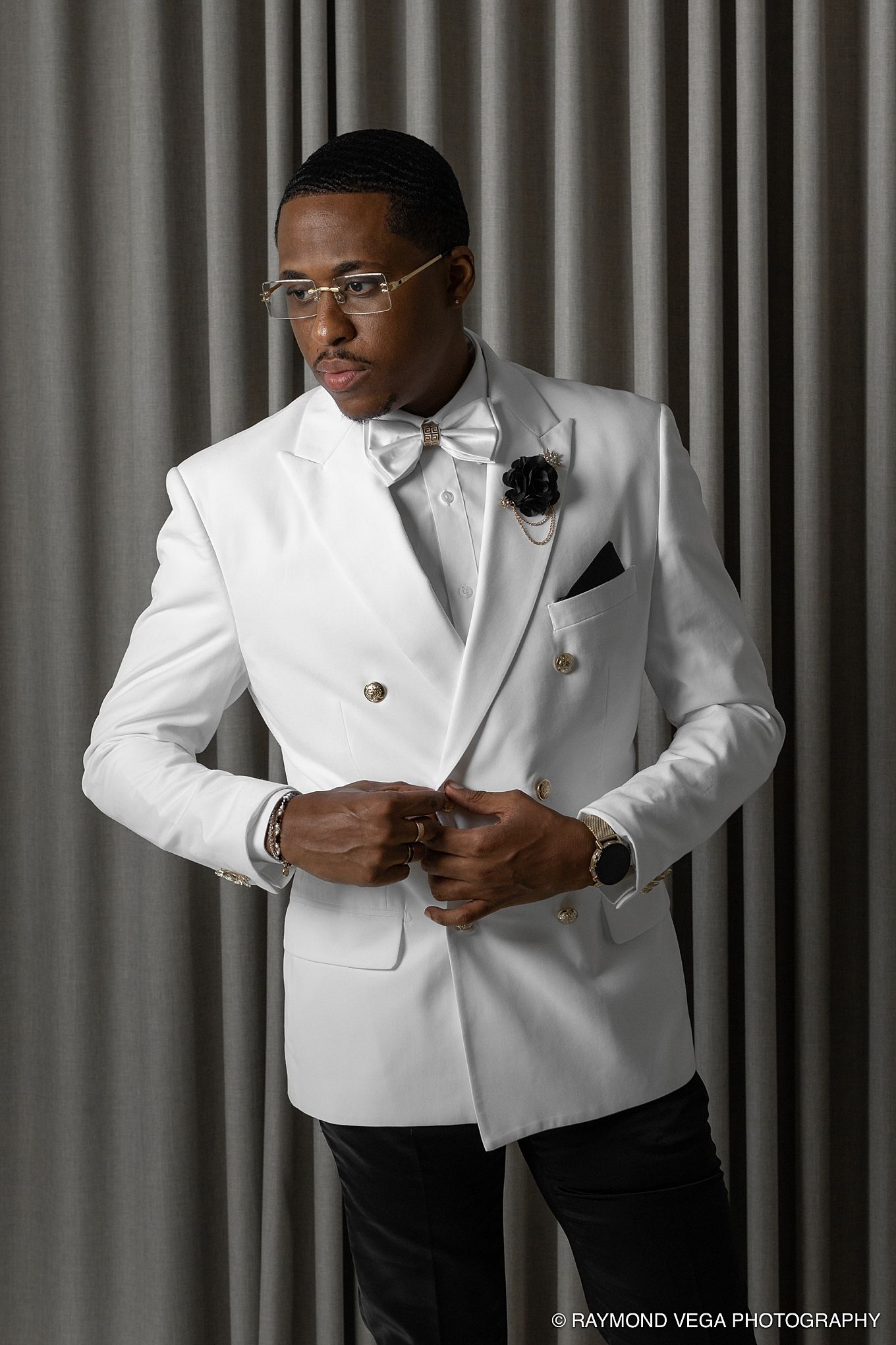Elegant man in white double-breasted tuxedo jacket with bow tie and black boutonniere, posing confidently. Hotel Condado Vanderbilt