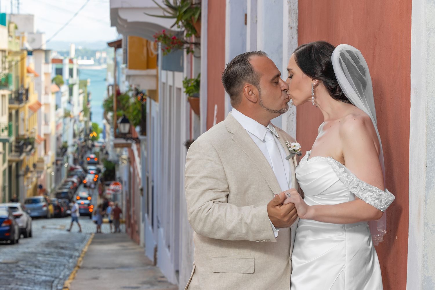 Bride and groom kissing on a colorful cobblestone street in Old San Juan, Puerto Rico, wearing wedding attire.