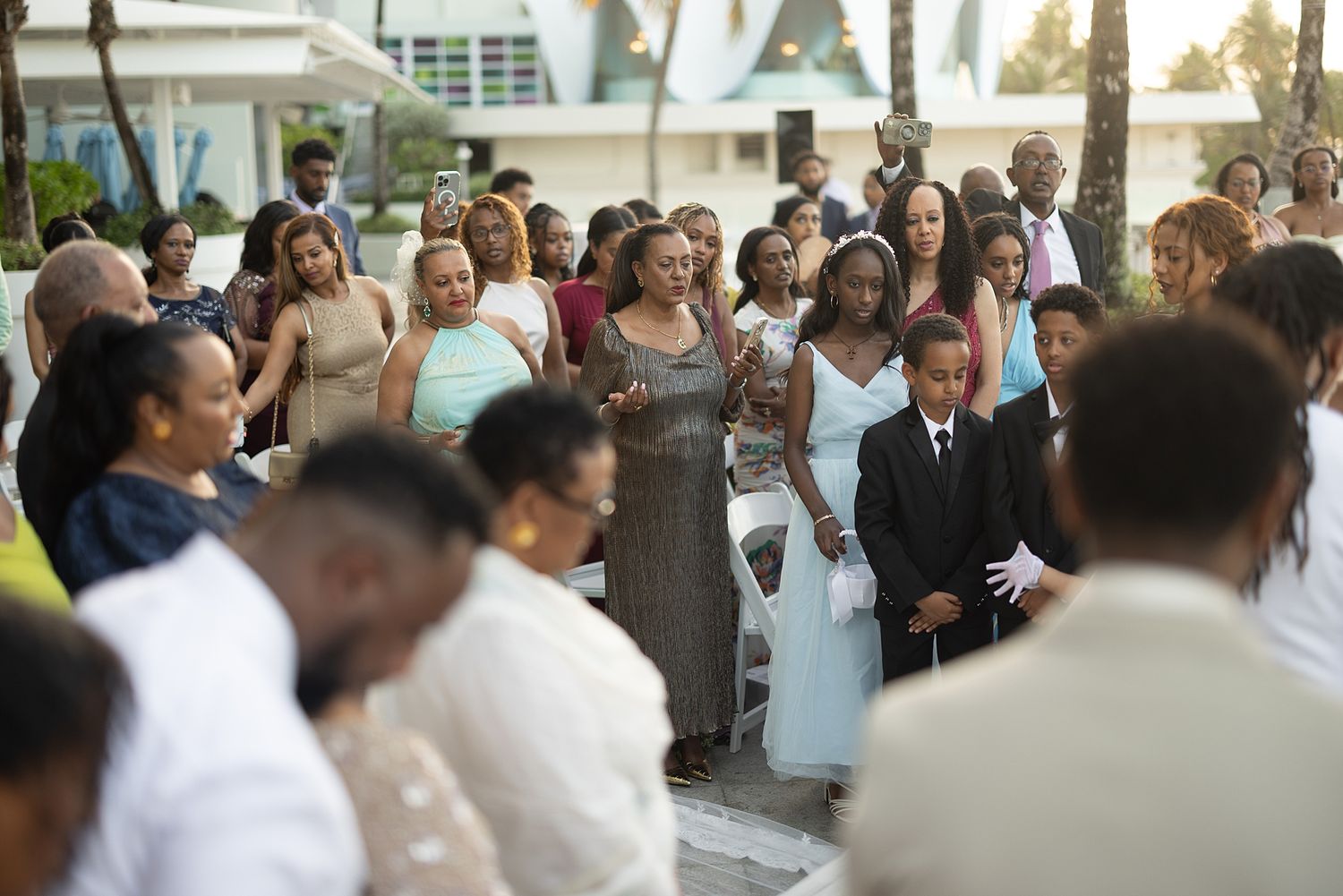 Guests gathered at an outdoor wedding ceremony, dressed in elegant attire, on a sunny day at a seaside venue. Hotel La Concha Puerto Rico