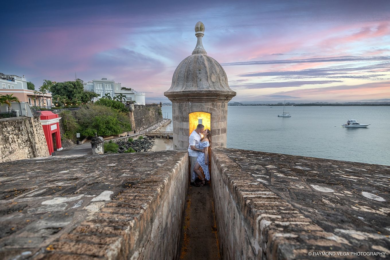Couple embracing in a historic stone sentry box at sunset overlooking the ocean in Old San Juan, Puerto Rico. - Love Story