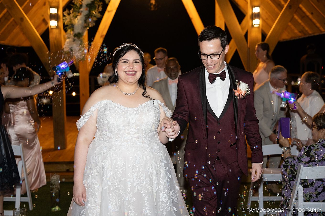 Happy newlywed couple walks hand-in-hand through a sparkler send-off at an elegant outdoor wedding venue.