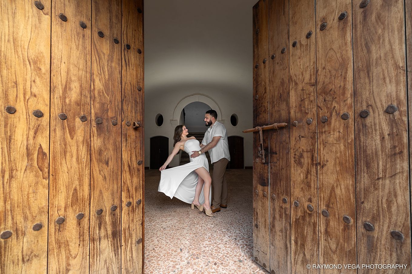 Couple dancing romantically through large wooden doors at a Mexican hacienda wedding venue.