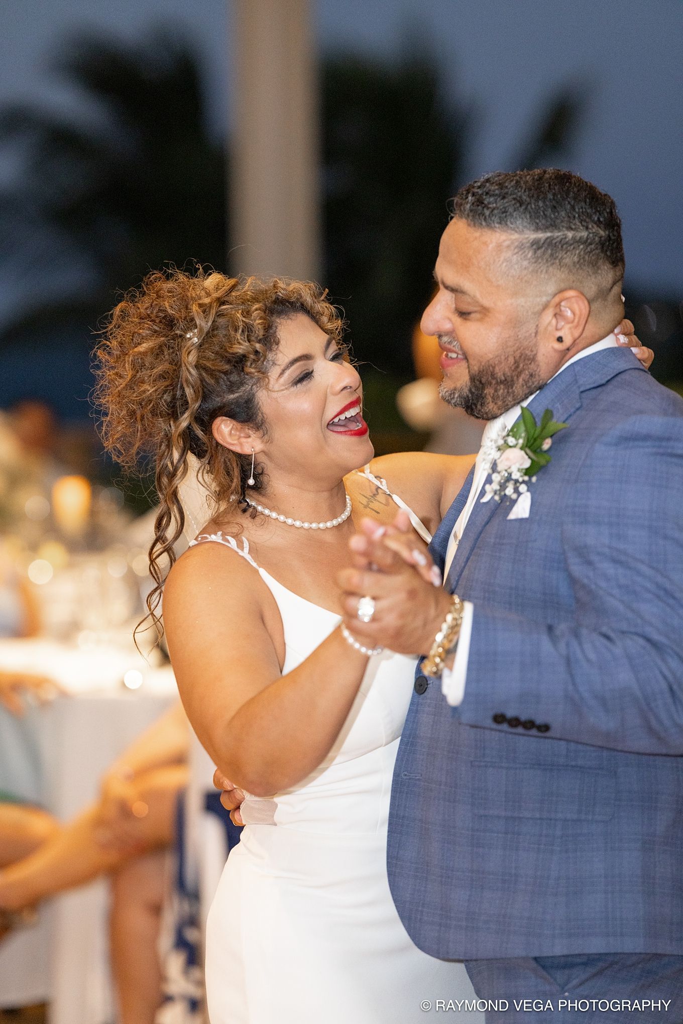 Bride and groom share their first dance, smiling joyfully, at an outdoor wedding reception at dusk at Courtyard by Marriott.