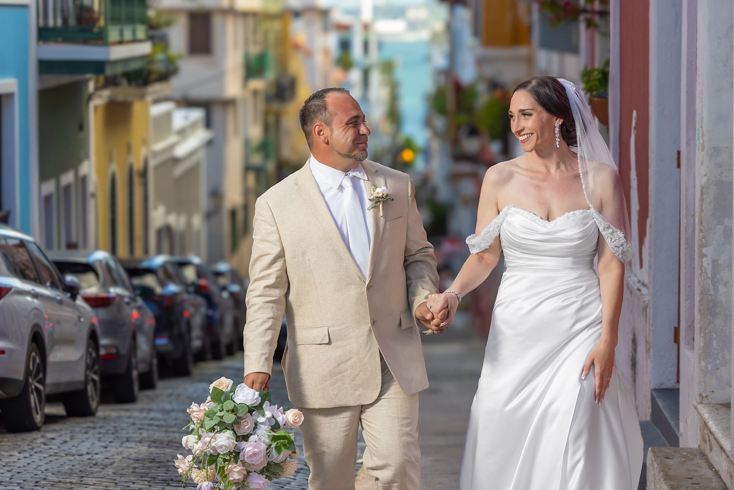 Bride and groom walk hand-in-hand on colorful cobblestone street in Old San Juan, Puerto Rico on their wedding day. The Cannon Club