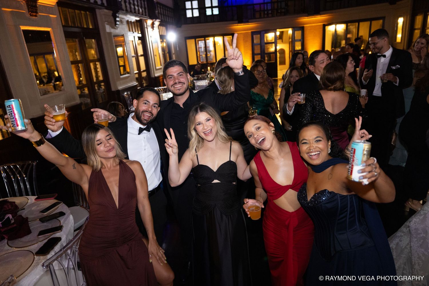 Group of elegantly dressed friends posing and celebrating at a formal evening gala event.