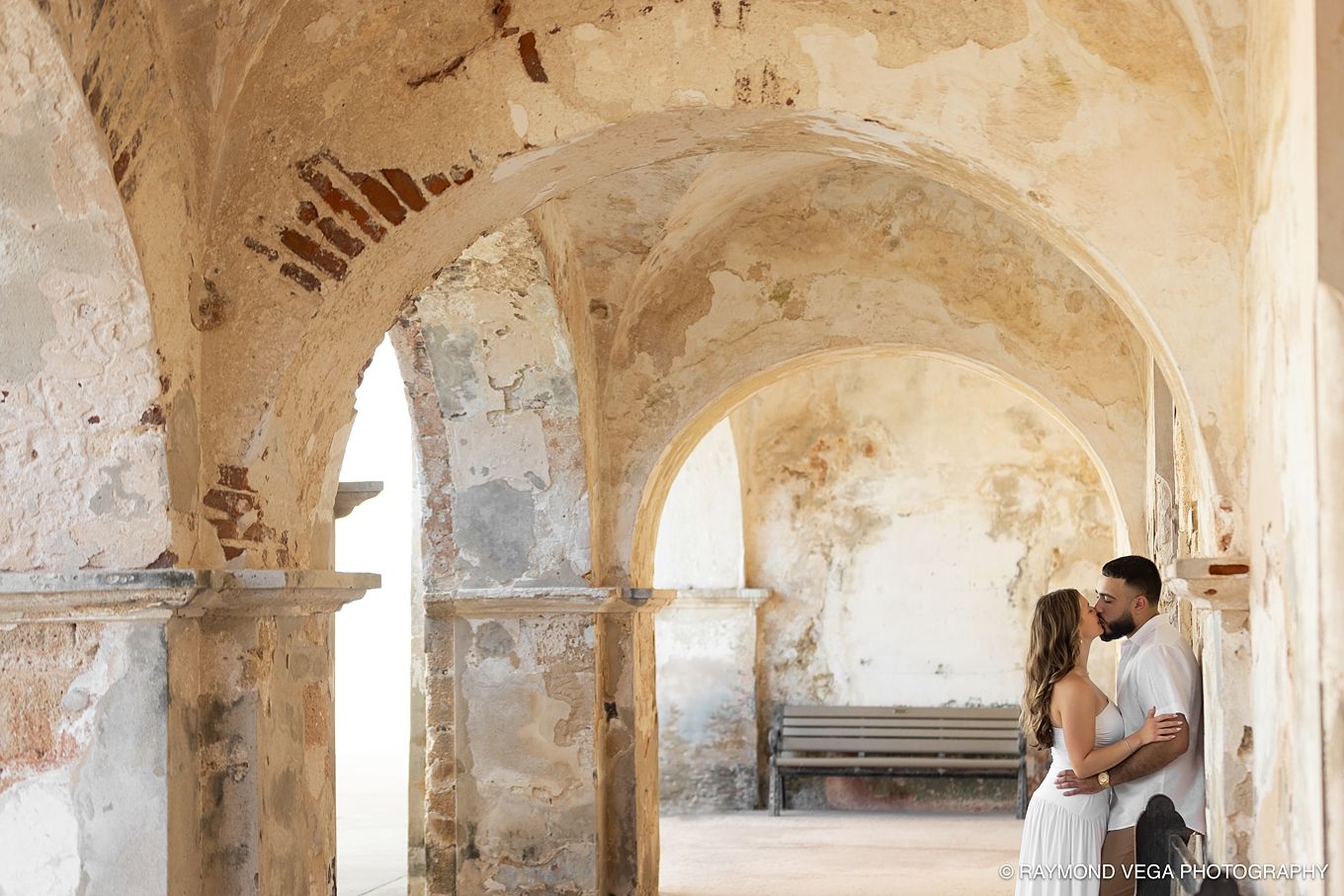Couple sharing a romantic moment under ancient stone arches in a historic ruins venue.