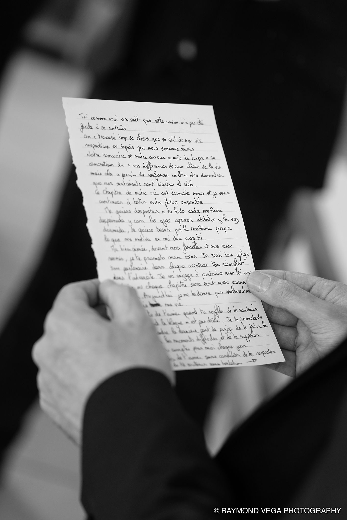 Black and white photo of hands holding a handwritten letter, captured by Raymond Vega Photography.