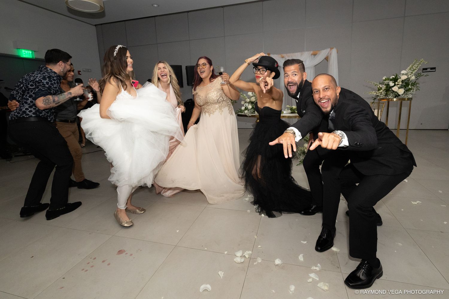 Joyful wedding reception with bride in white gown dancing and celebrating with guests on a white dance floor.