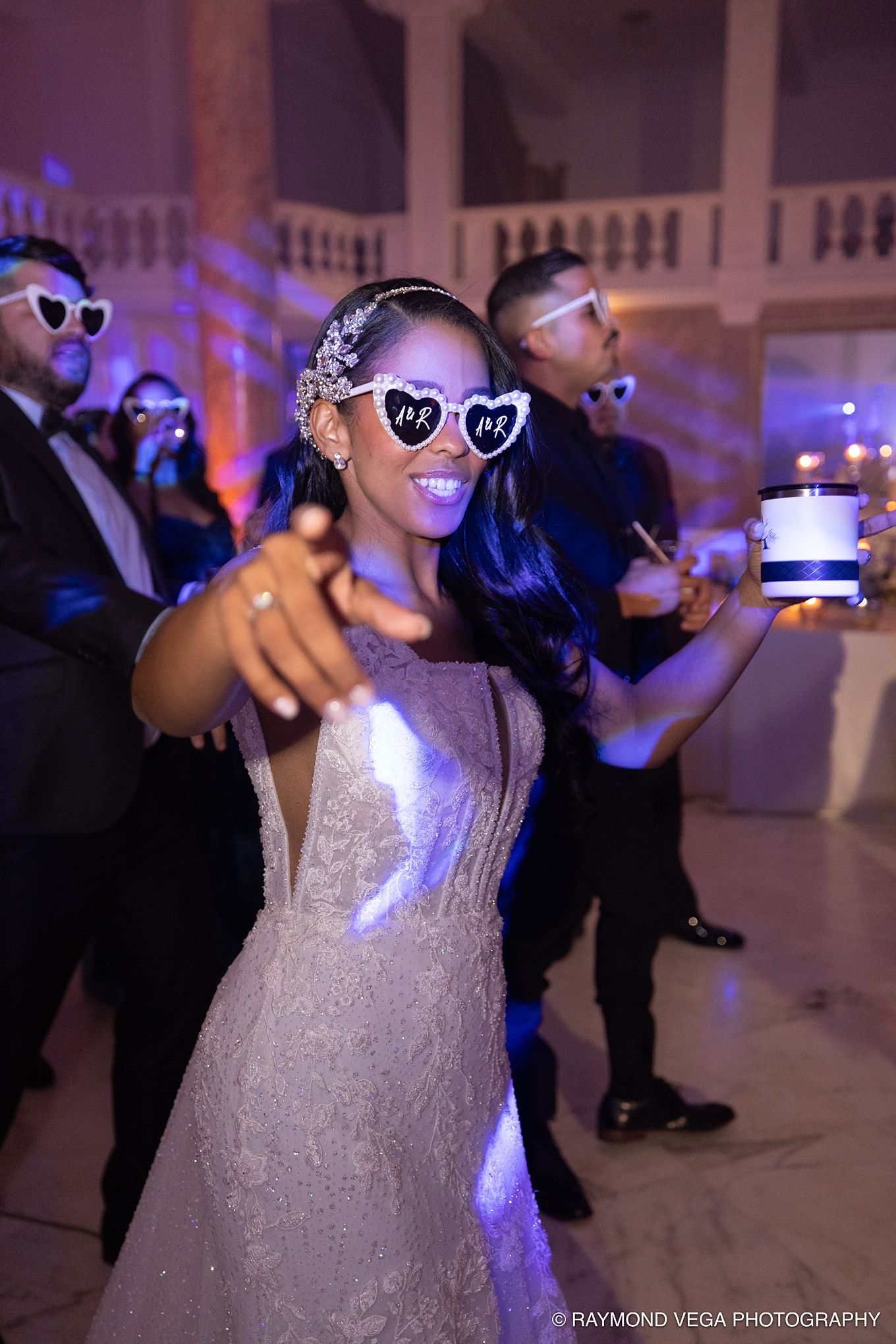 Bride in sparkly gown and heart-shaped Mr & Mrs sunglasses dancing joyfully at elegant wedding reception.Antiguo Casino Puerto Rico wedding