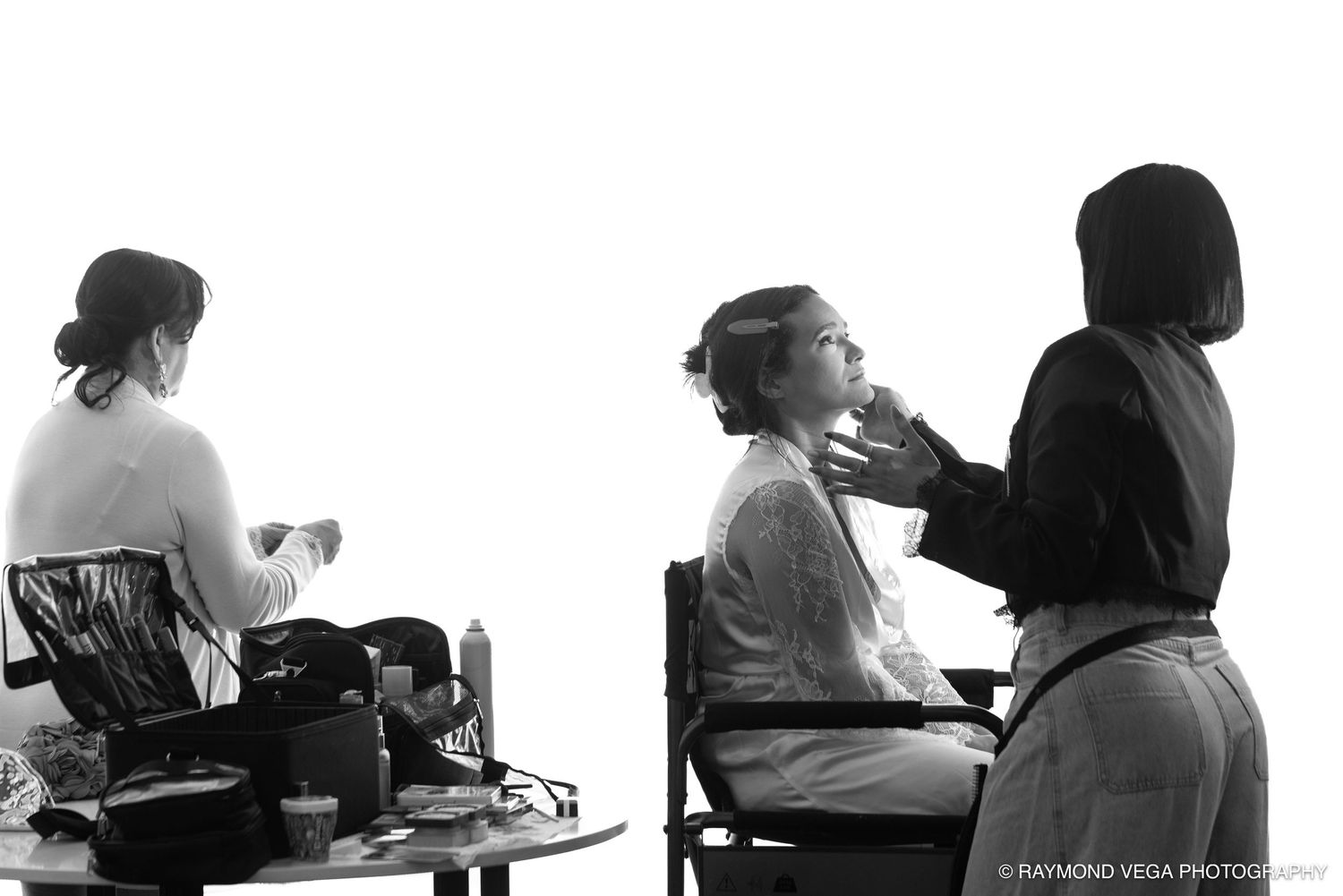 Black and white photo of bridesmaids getting makeup done before a wedding ceremony.