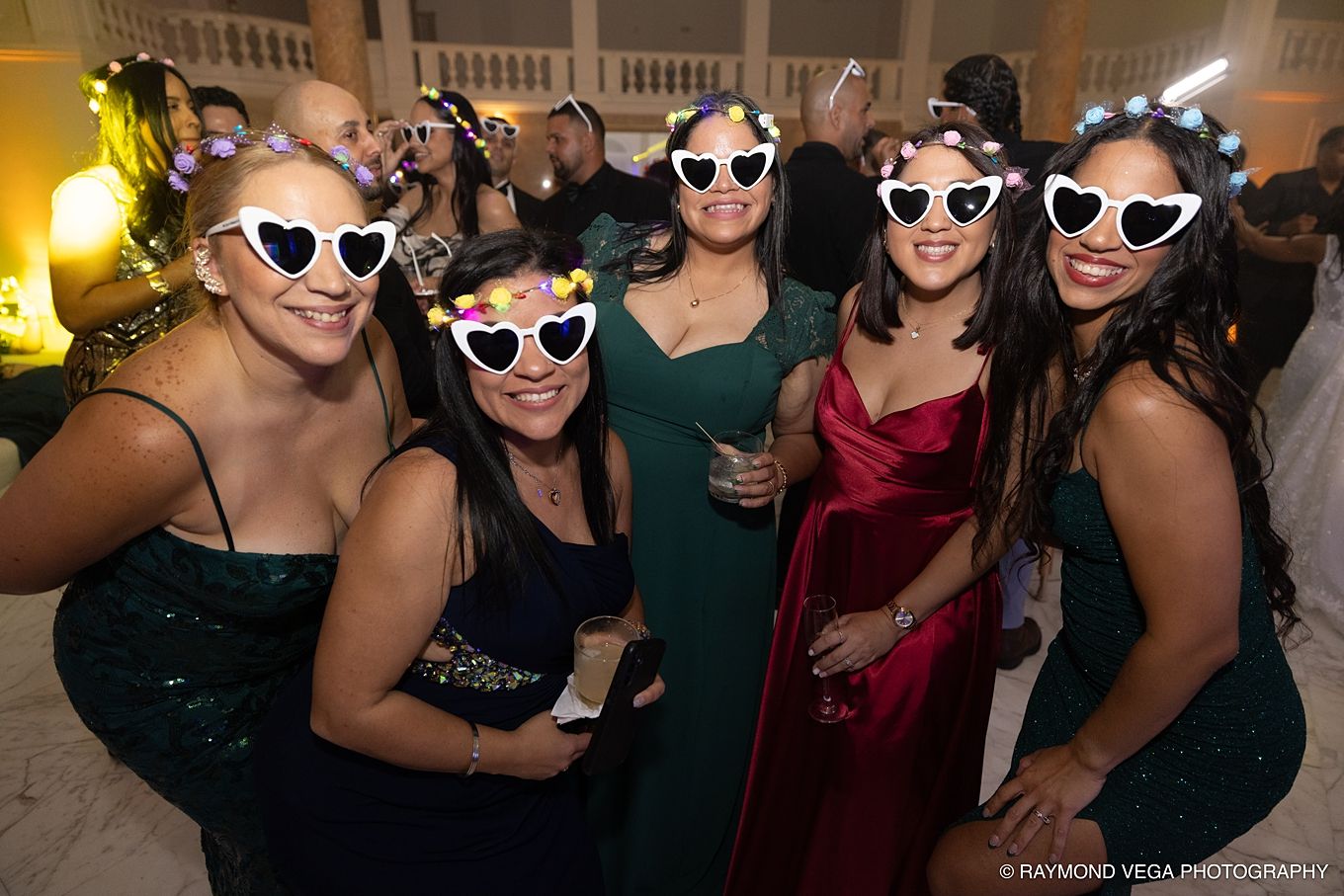Five women in elegant dresses and heart-shaped sunglasses pose together at a formal evening event.Antiguo Casino Puerto Rico wedding