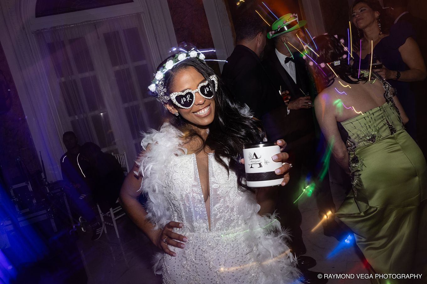 Woman in white feathered dress and heart sunglasses holds a gift box at an elegant evening party. Antiguo Casino Puerto Rico wedding