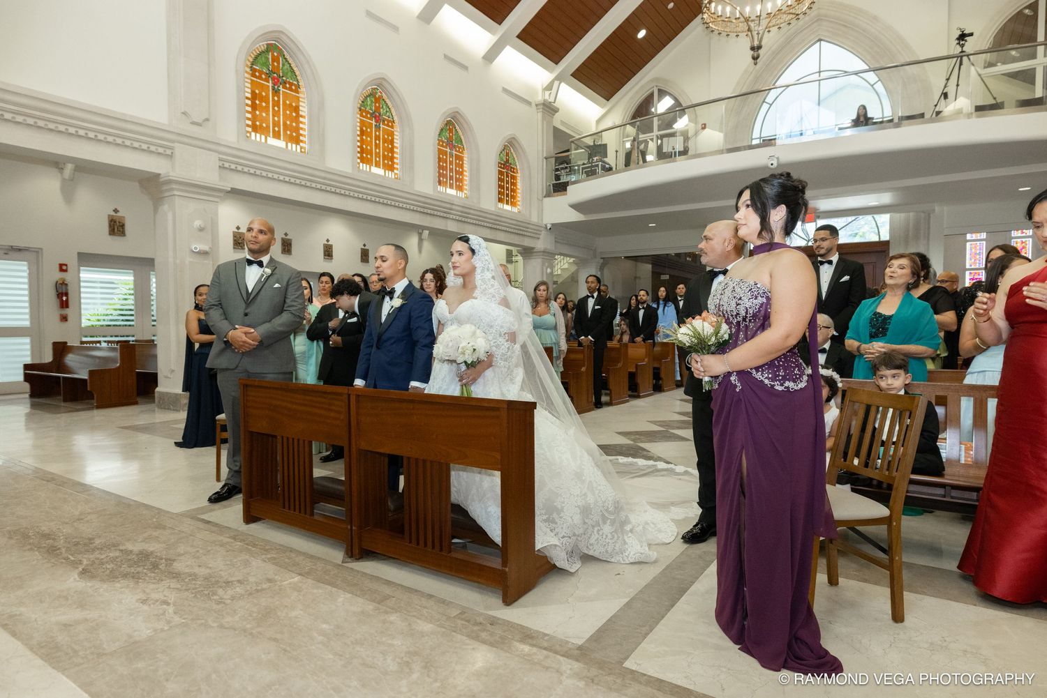 Bride in white gown walks down church aisle with escort during elegant wedding ceremony.
