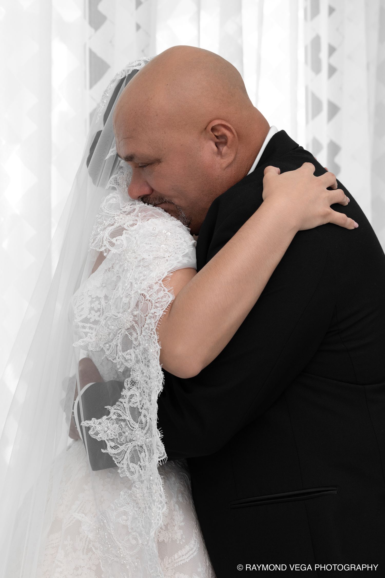 Emotional bride and groom sharing a tender embrace on their wedding day, captured by Raymond Vega Photography.