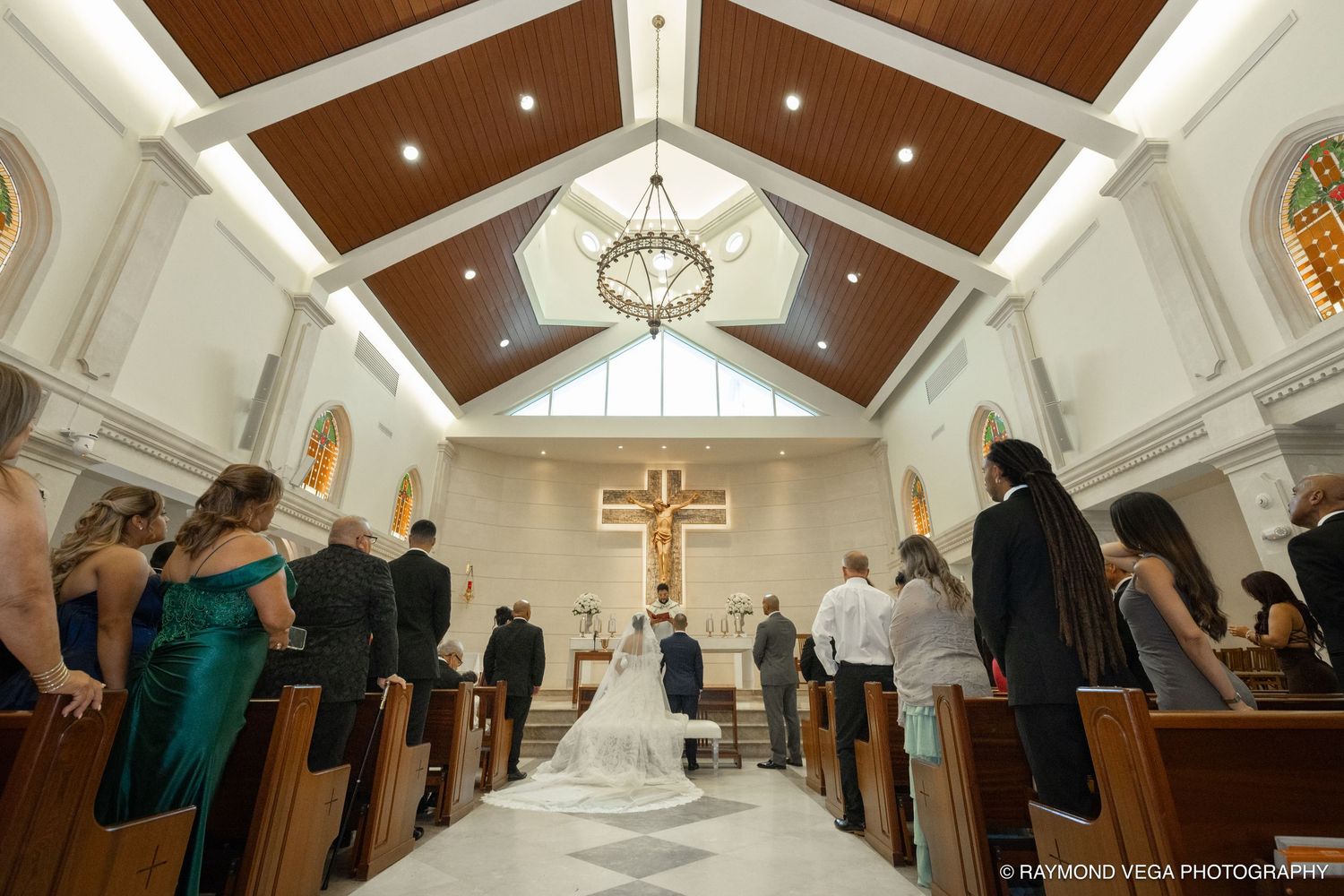 Bride and groom at the altar during a church wedding ceremony with guests seated in wooden pews.