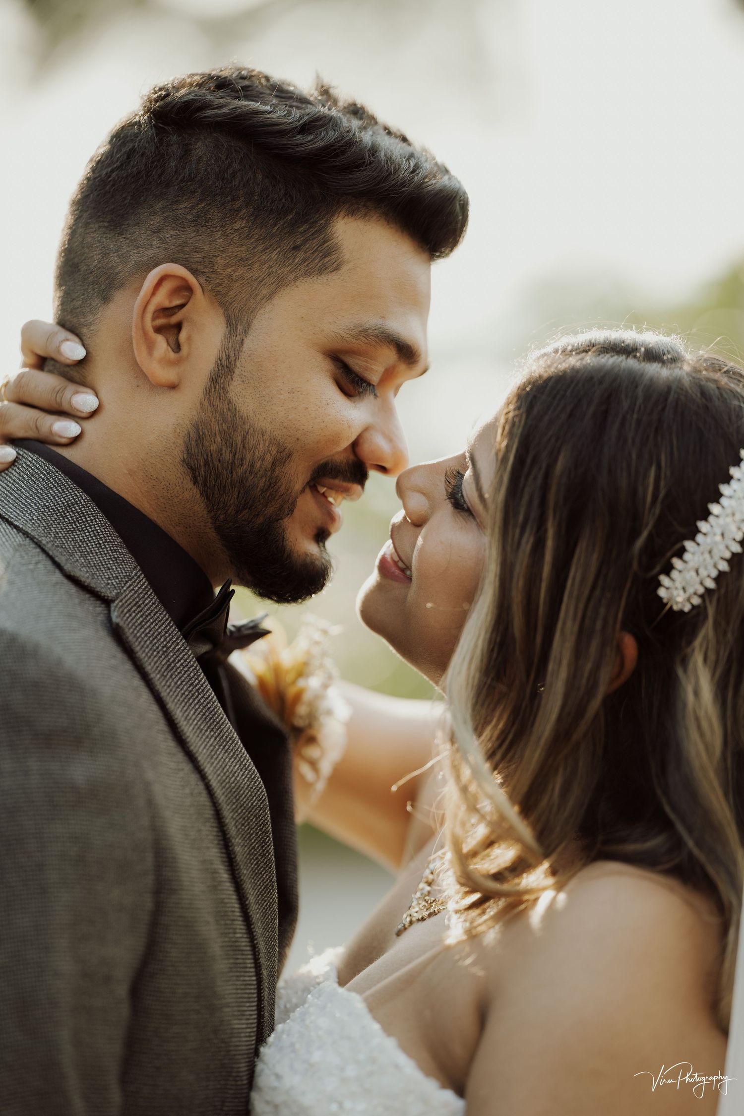 A romantic wedding couple share an intimate moment outdoors in glowing natural light.