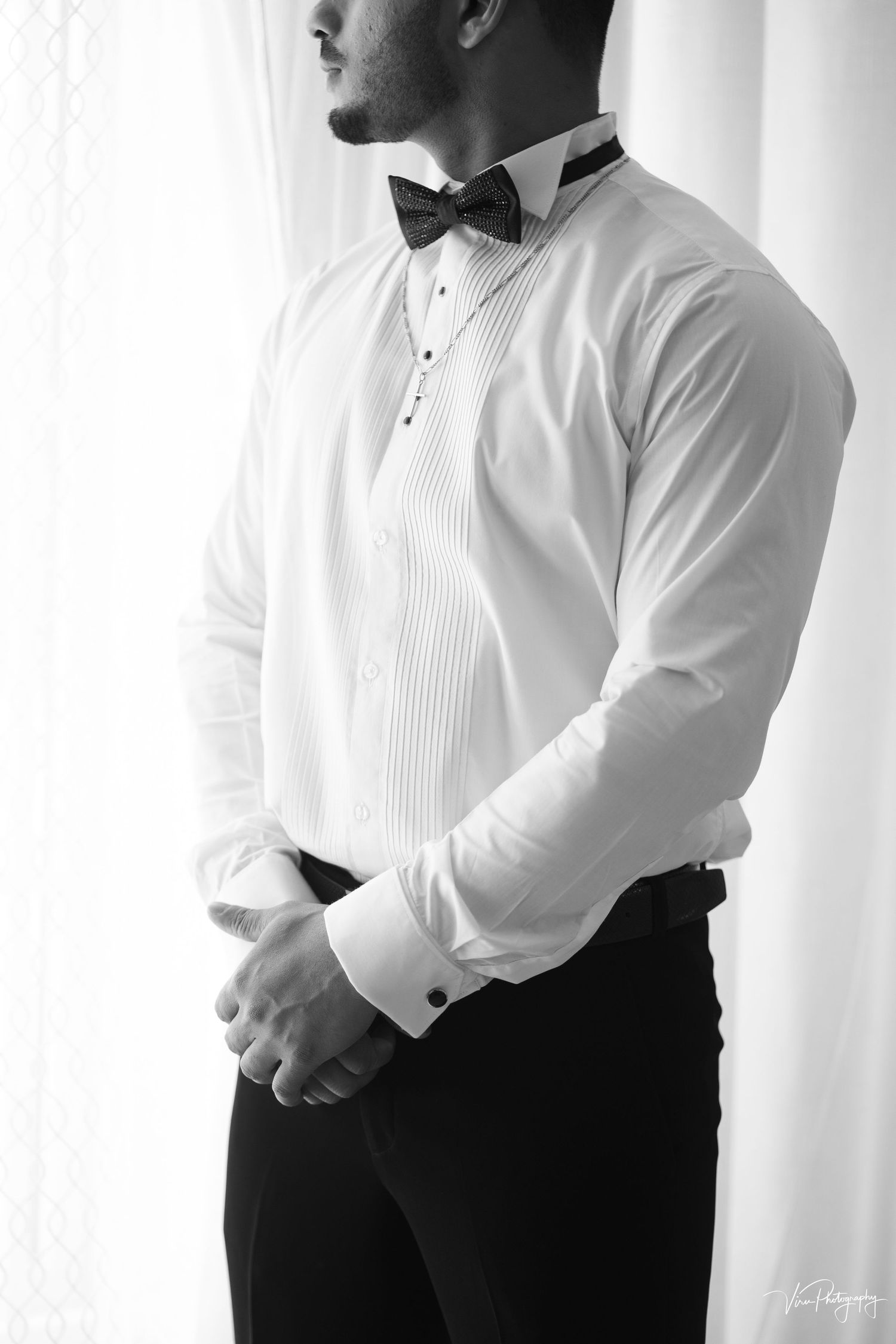Black and white photo showing crisp tuxedo shirt with pleated bib front and bow tie in formal attire.