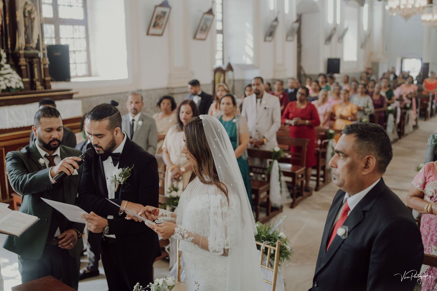 Traditional church wedding ceremony with guests seated in pews while couple exchanges vows at the altar.