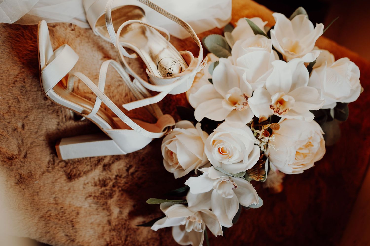 White roses and ribbons arranged on a rustic brown surface with soft lighting.