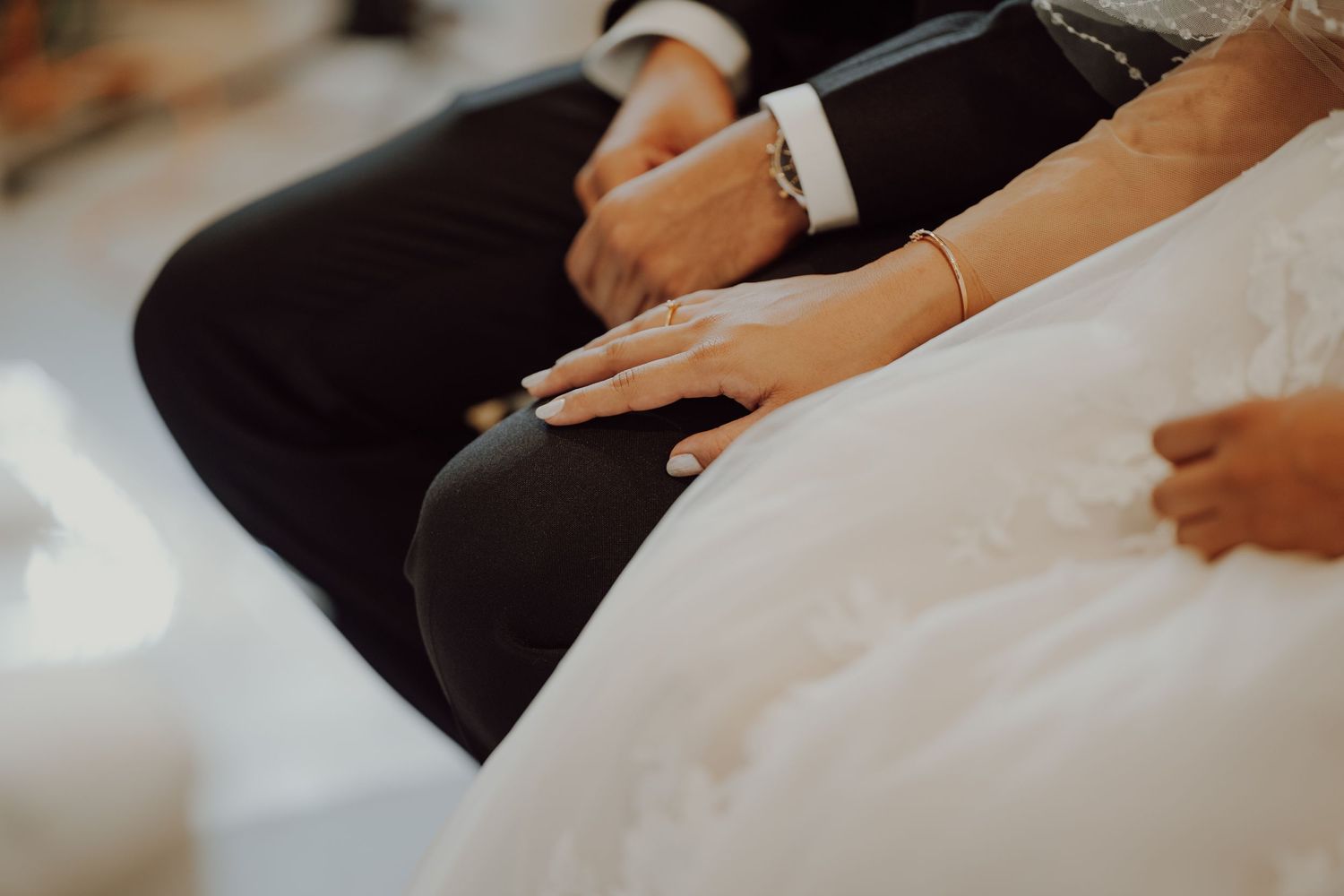 Close-up detail shot of wedding attire showing hands resting on formal wear.