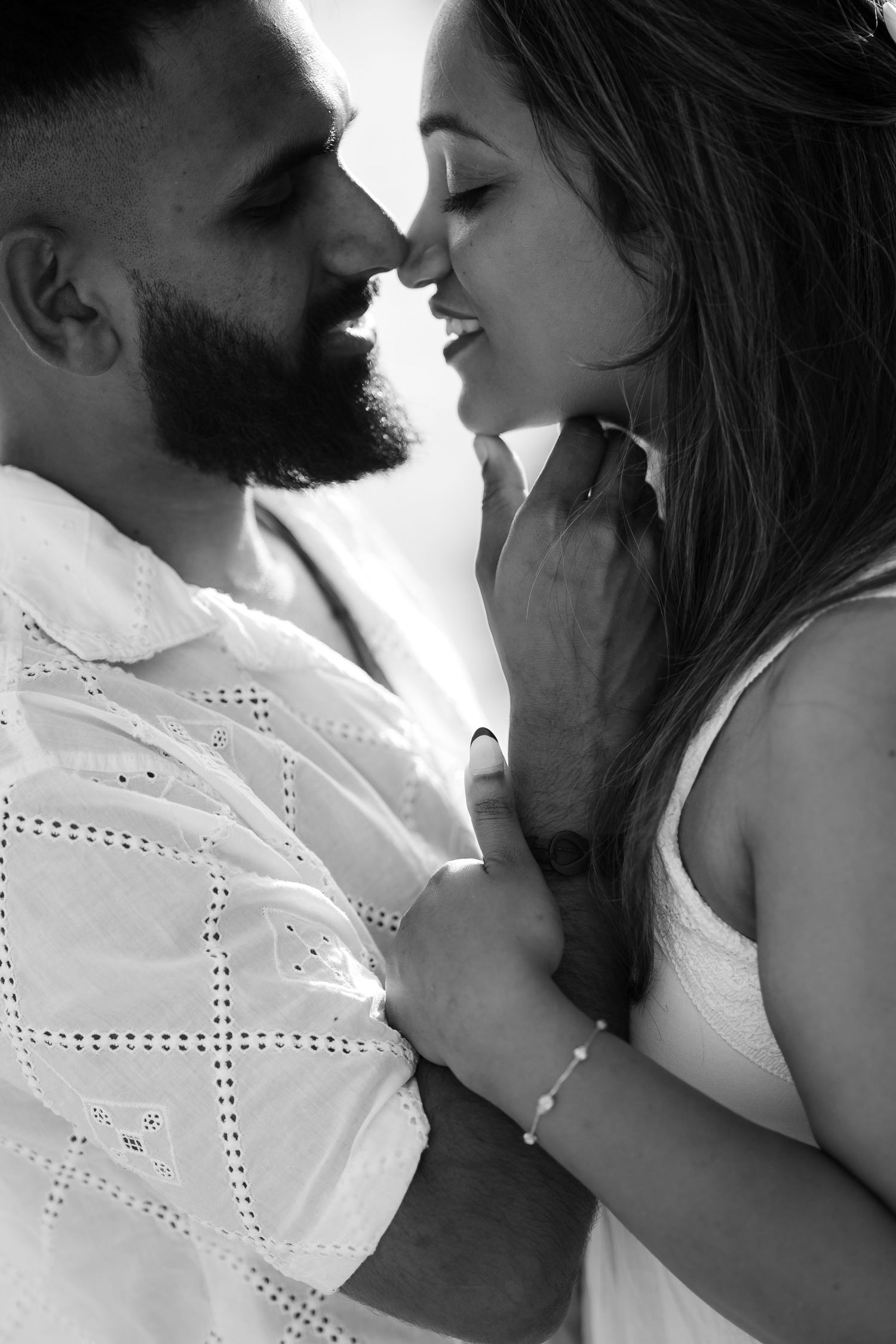 A romantic black and white close-up of a couple about to kiss, with the woman in a white top and man in embroidered shirt.