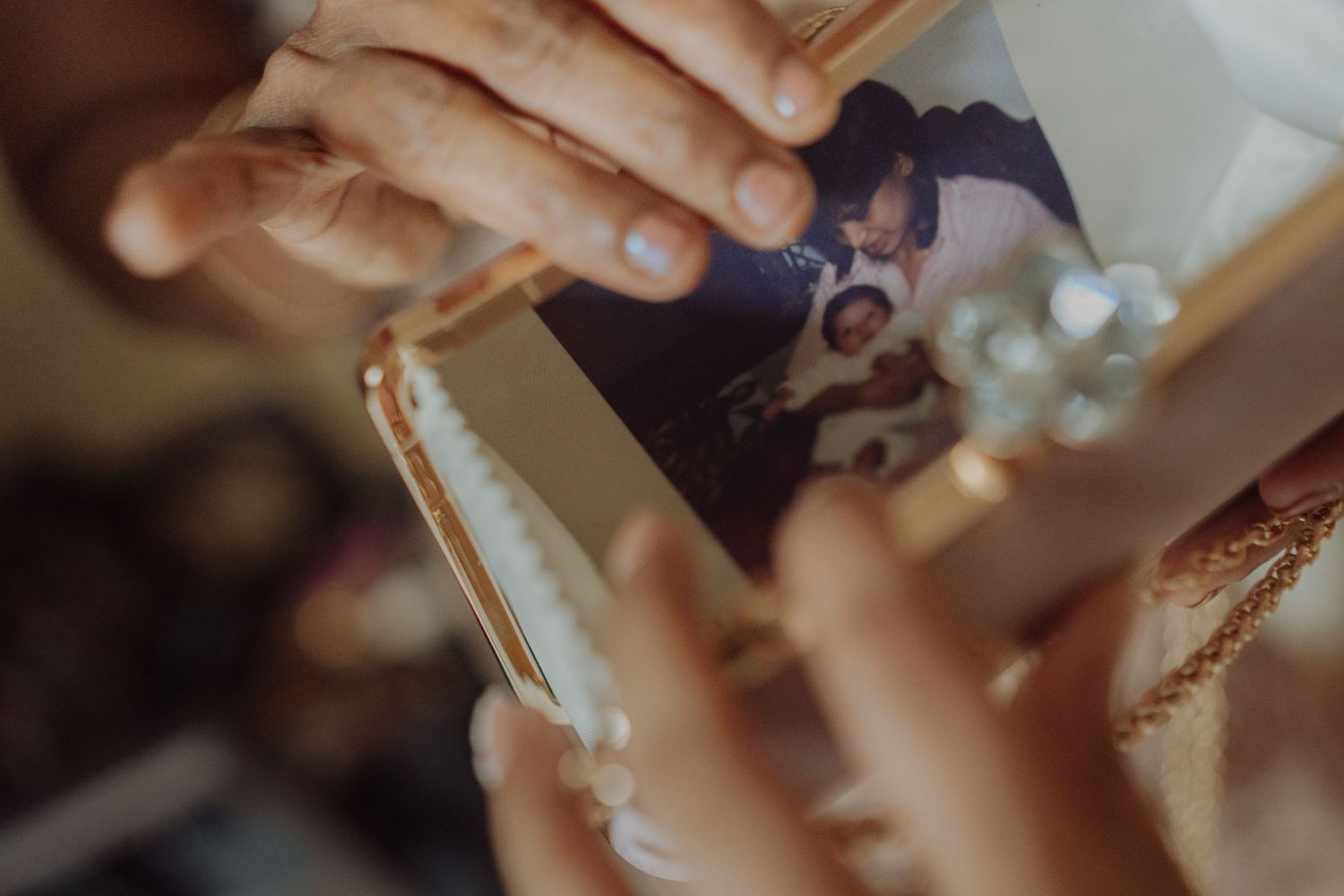 Hands hold a gold-framed vintage family photograph, a sentimental keepsake being cherished on a wedding day.