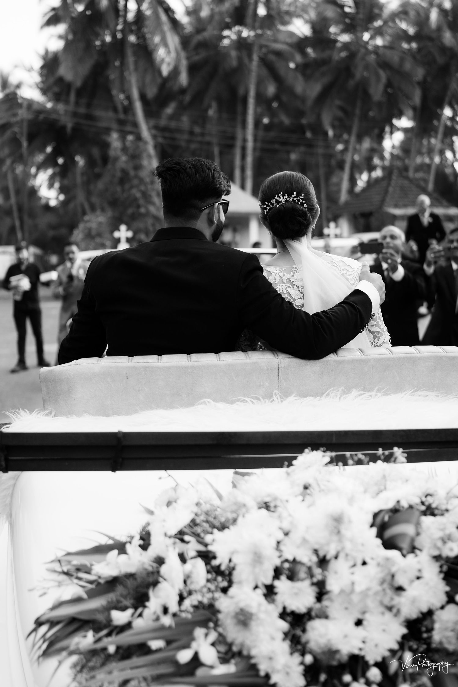 A romantic black and white wedding photo showing a couple sitting together with floral decorations in the foreground.