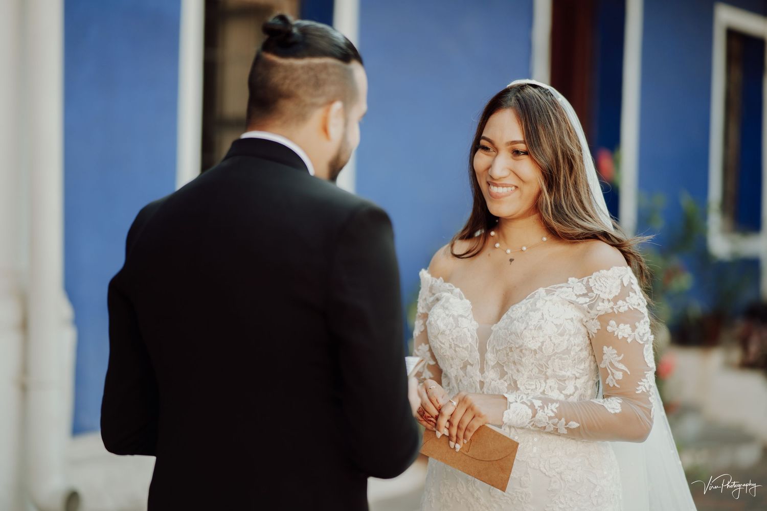 A couple shares a tender moment during their wedding ceremony with the bride wearing an elegant lace long-sleeved gown.
