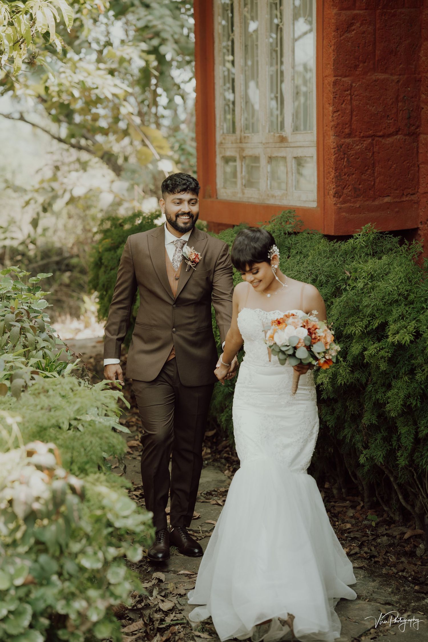 A couple shares a sweet moment together during their wedding in a garden setting with autumn flowers and greenery.