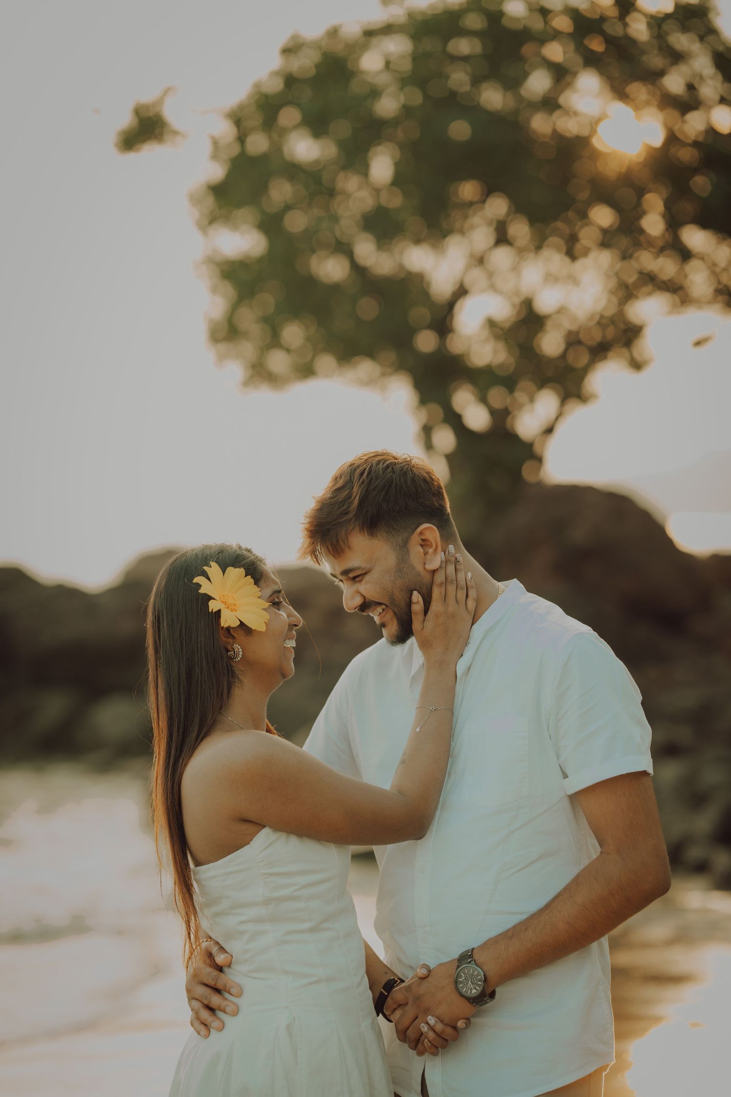 A couple shares intimate moments during a romantic sunset photoshoot on the beach.