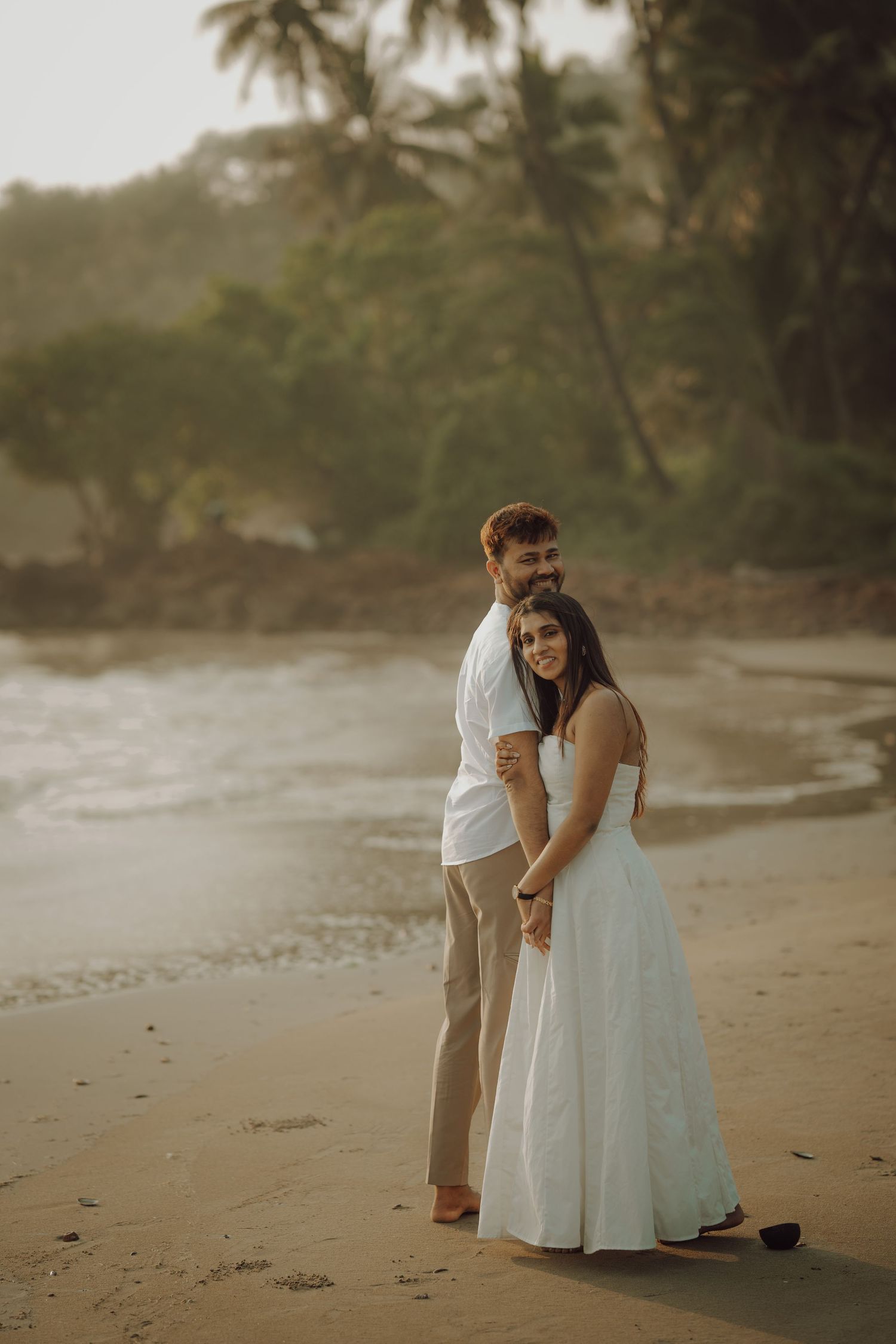 A romantic beach wedding moment captured at sunset with palm trees swaying in the background.