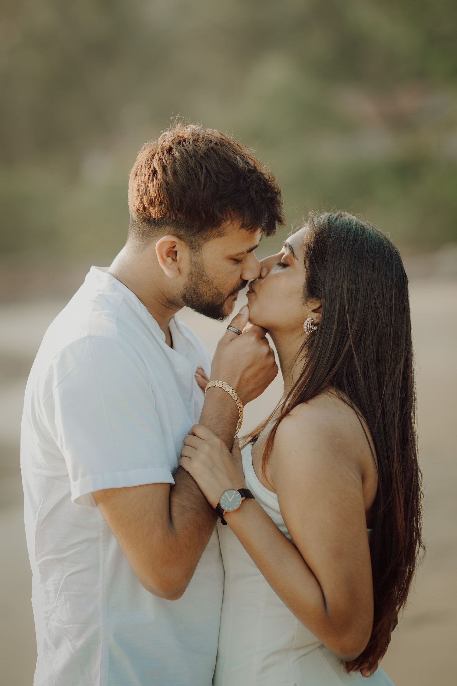 A romantic couple in white outfits share tender kisses in a series of intimate outdoor portrait photographs.