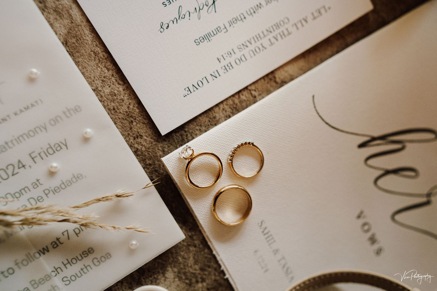 Wedding rings artistically arranged with elegant white invitations on a textured surface.