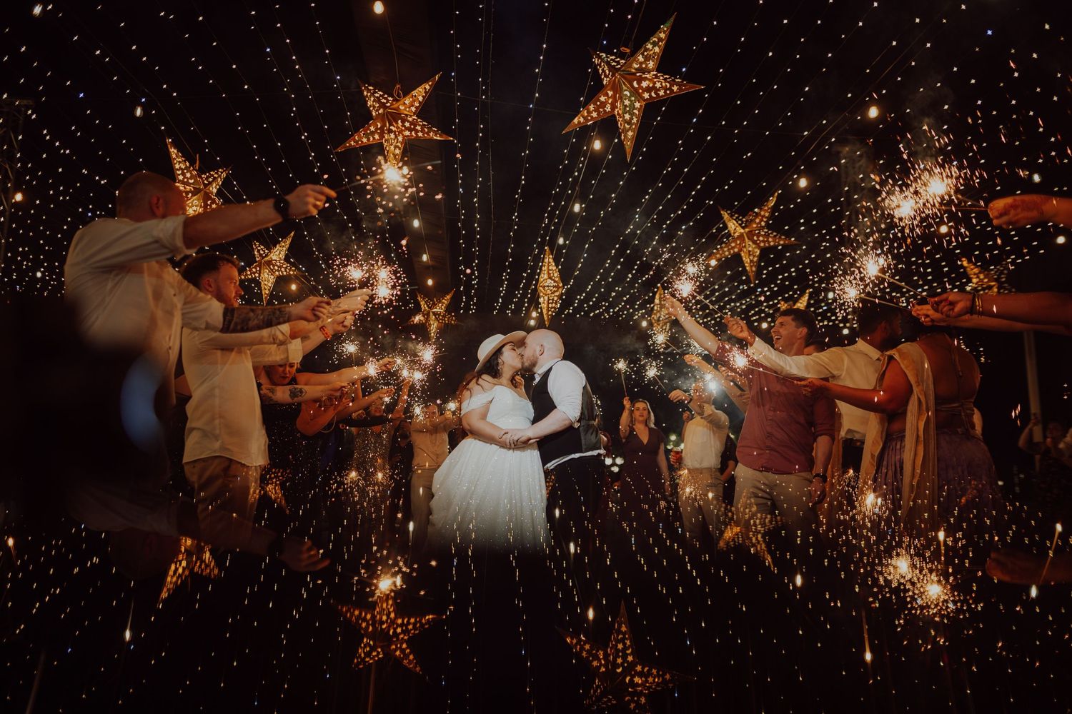 Wedding celebration with sparklers and illuminated star decorations creating magical nighttime atmosphere.