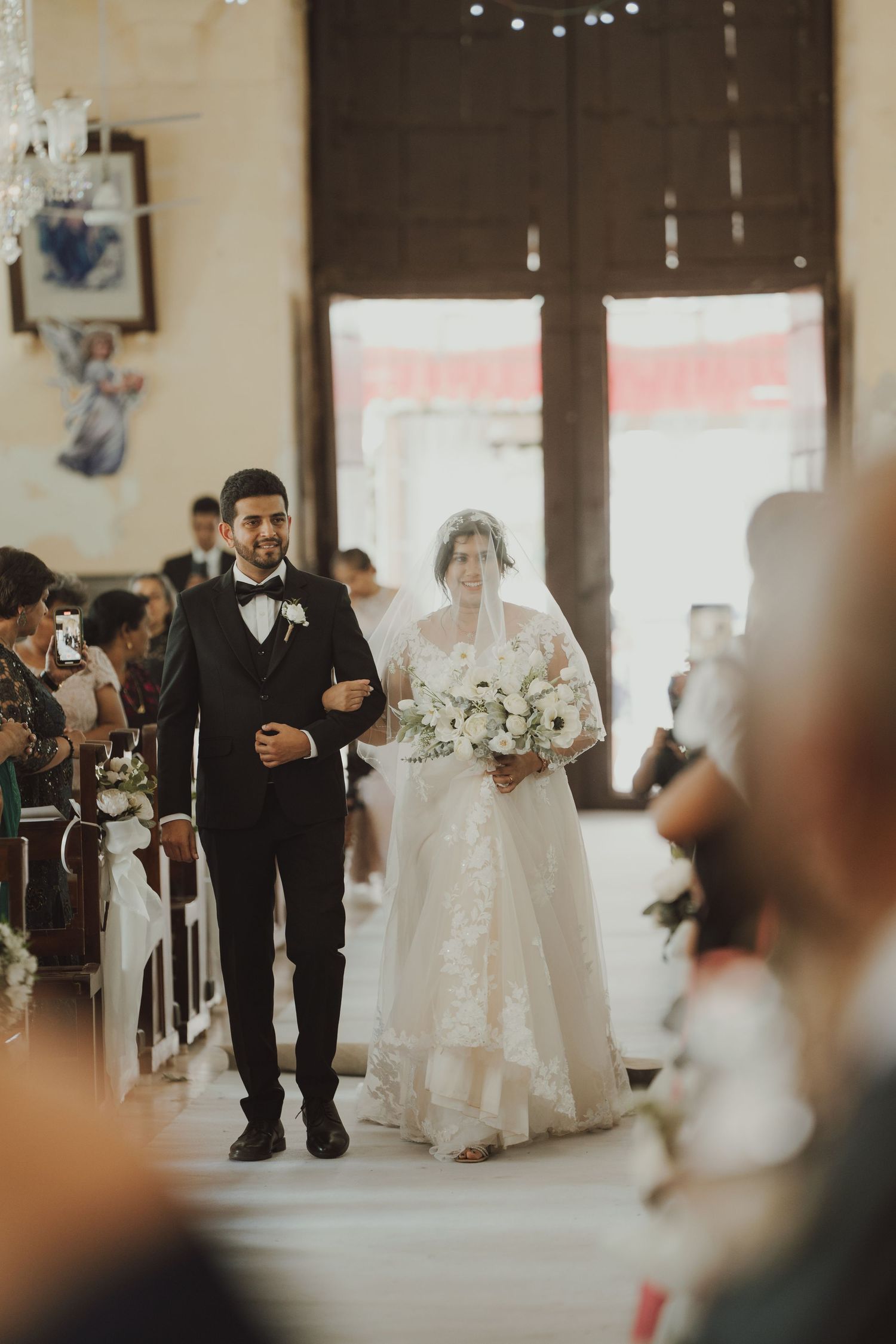 A wedding ceremony procession in a beautifully lit church interior.