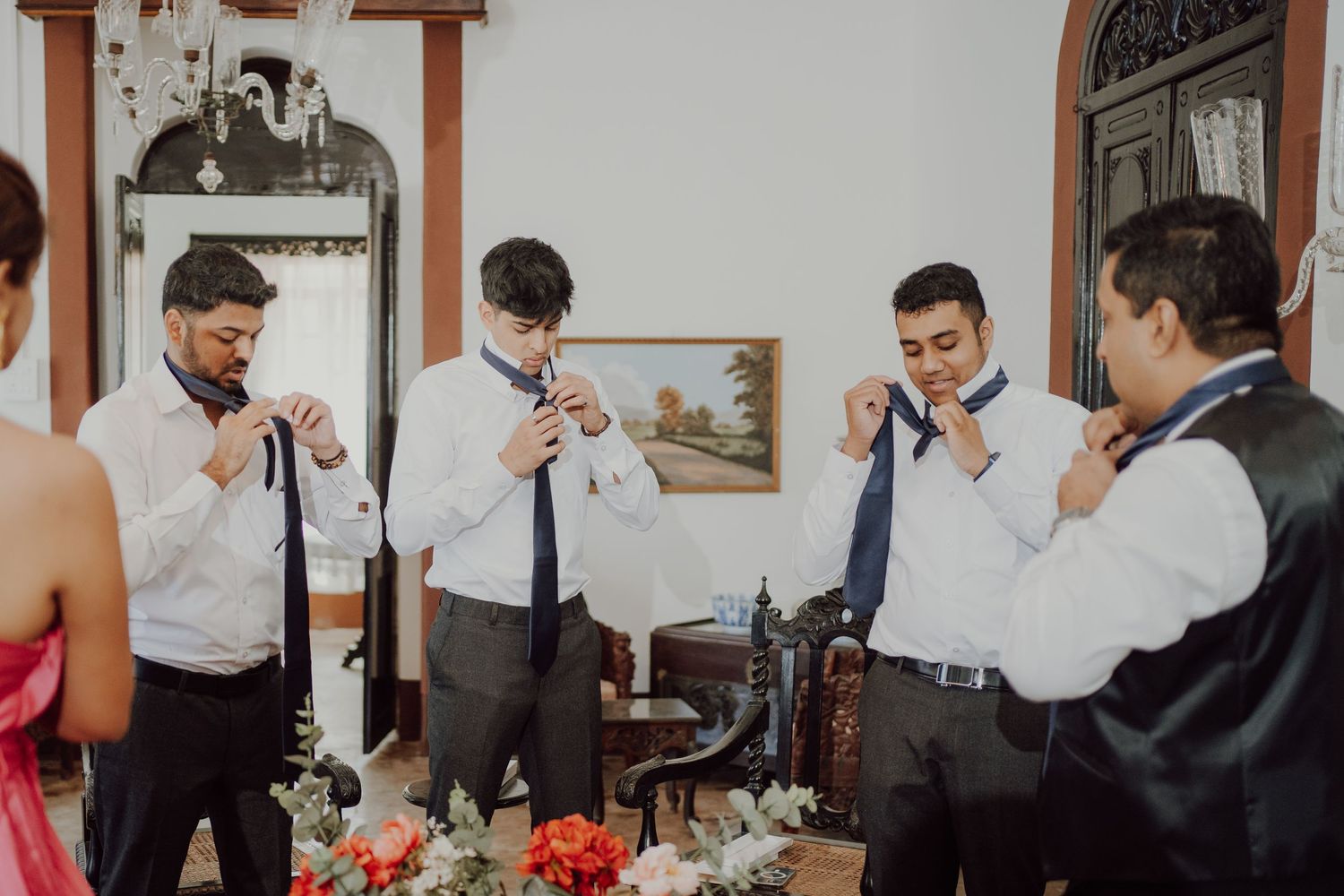 Groomsmen adjusting their ties while getting ready for wedding ceremony.